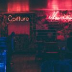 A dimly lit hair salon with neon signs glowing red and pink.