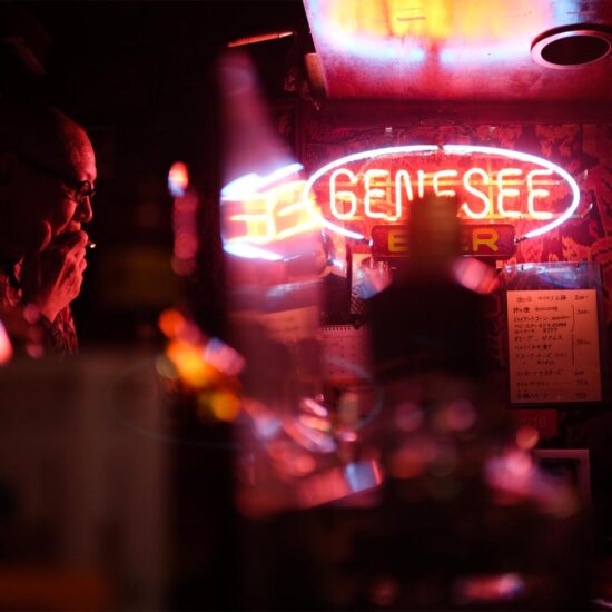 A neon Genesee sign glowing in a dim bar setting.