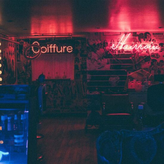 Dimly lit barber shop with red neon signs.