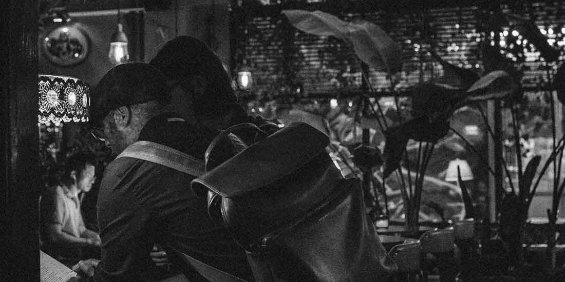 A couple embraces under twinkling lights at night.