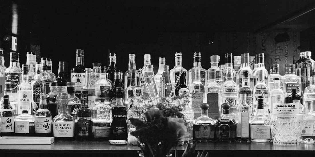 Black and white photo of a bar counter with bottles.
