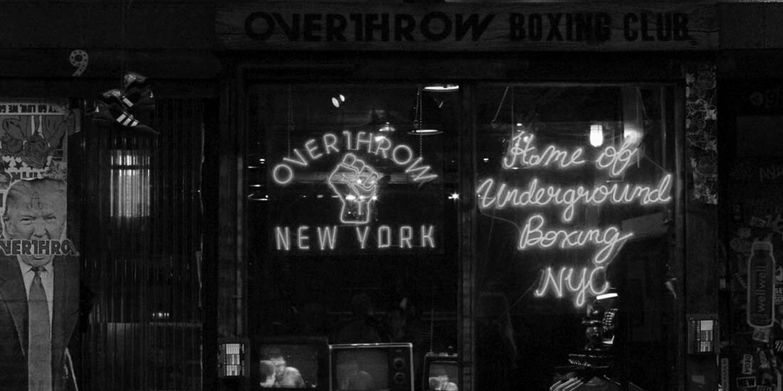 A black-and-white photo of a vintage storefront with a New York sign.
