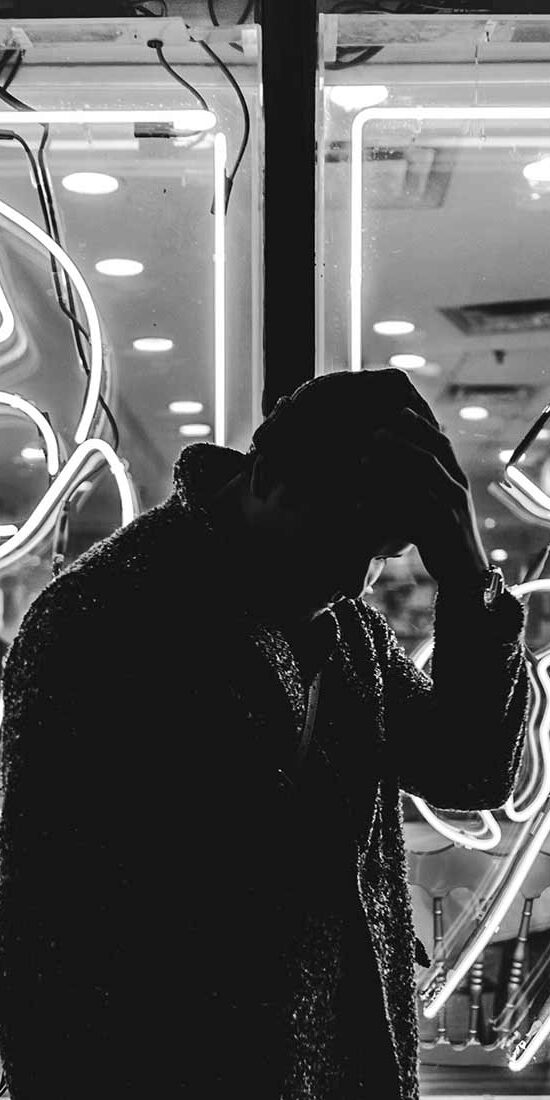 Silhouette of a person in front of bright neon fish signs.