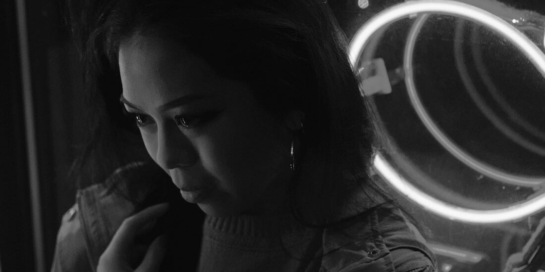 Black and white portrait of a woman with illuminated circular lights behind her.