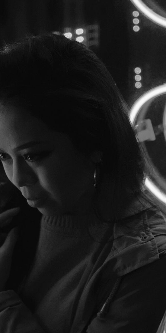 Black and white portrait of a woman with illuminated circular lights behind her.